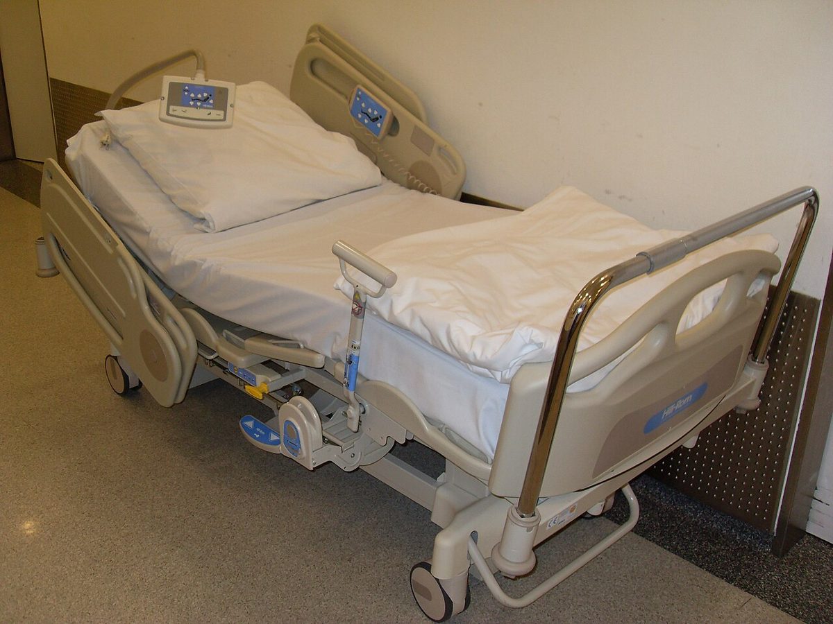 A hospital bed with side rails in a patient room